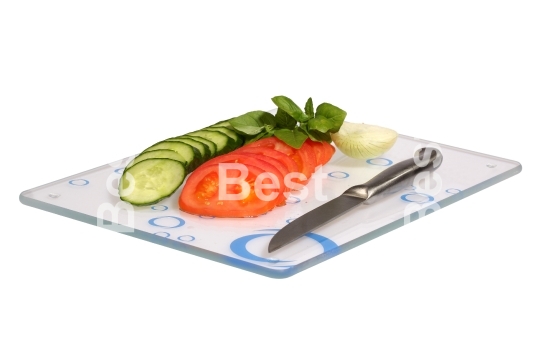 Cucumbers, onions, tomatoes on a glass cutting board