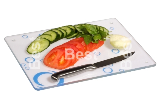 Cucumbers, onions, tomatoes on a glass cutting board