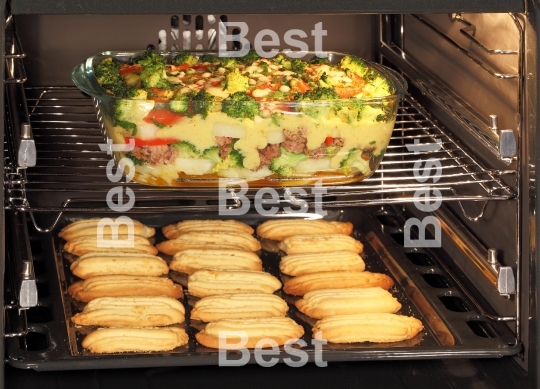 Homemade cookies and casserole dish in oven