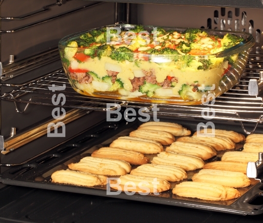 Homemade cookies and casserole dish in oven