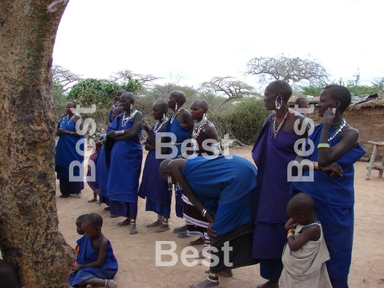 Masai performance in a traditional Masai village. Women with children singing and watching their men performance. 