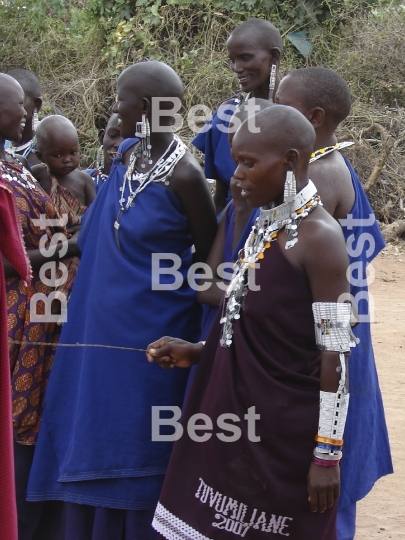 Masai performance in a traditional Masai village. Women with children singing and watching their men performance. 